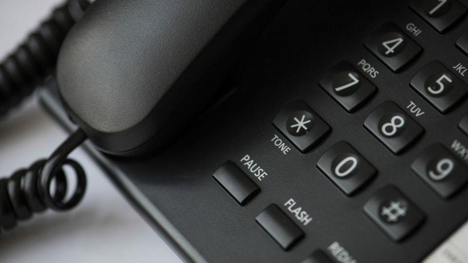 Close-up of a black wired office desk telephone with keypad and handset.