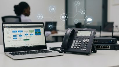 VoIP desk phone and laptop displaying 3CX cloud PBX phone system software in an office