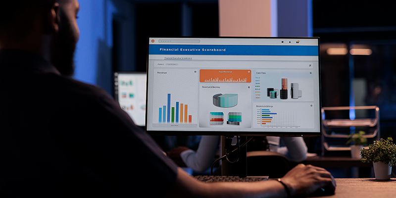 Professional analysing a financial data dashboard with charts on a desktop monitor